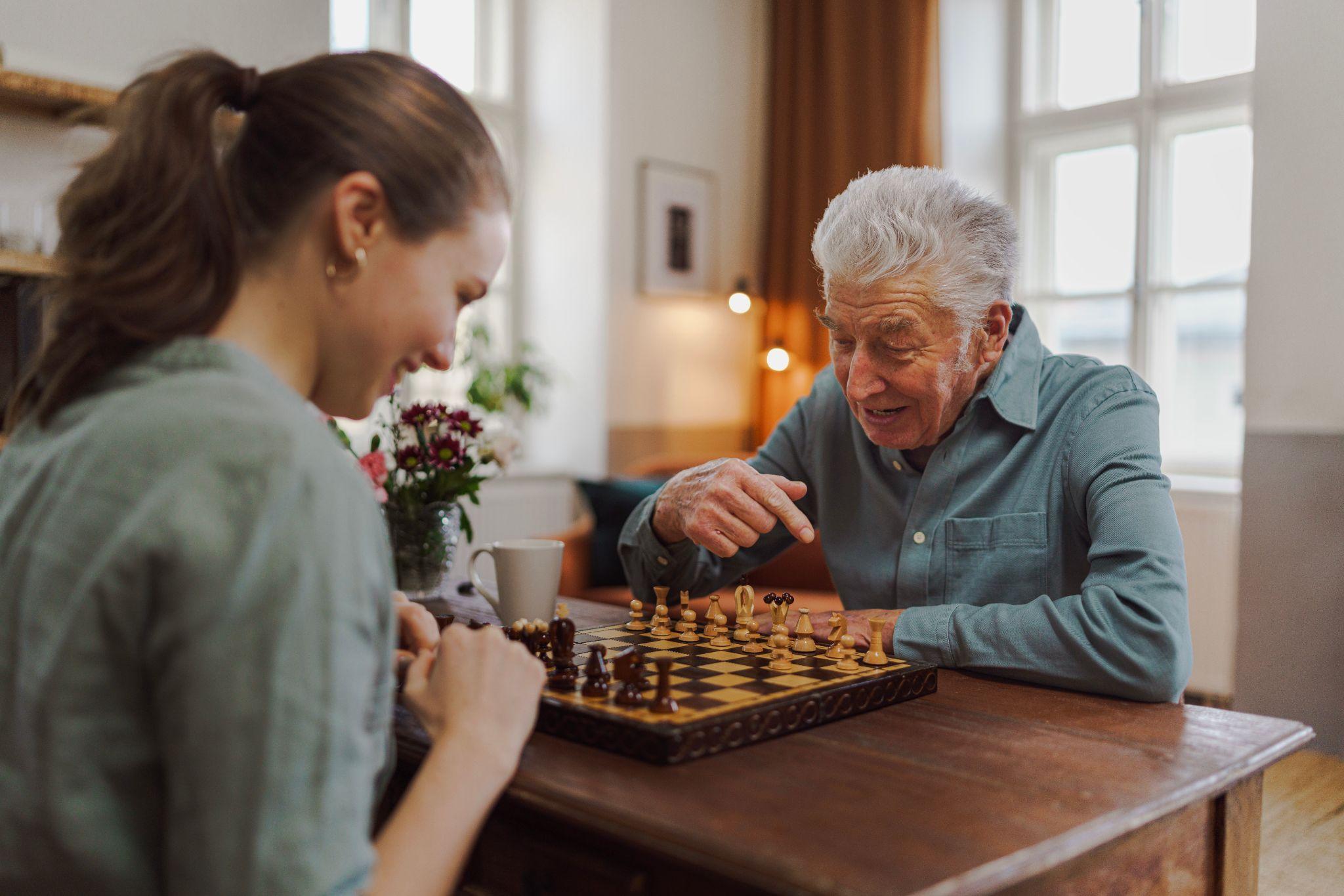 caregiver and senior playing chess during the cold winter